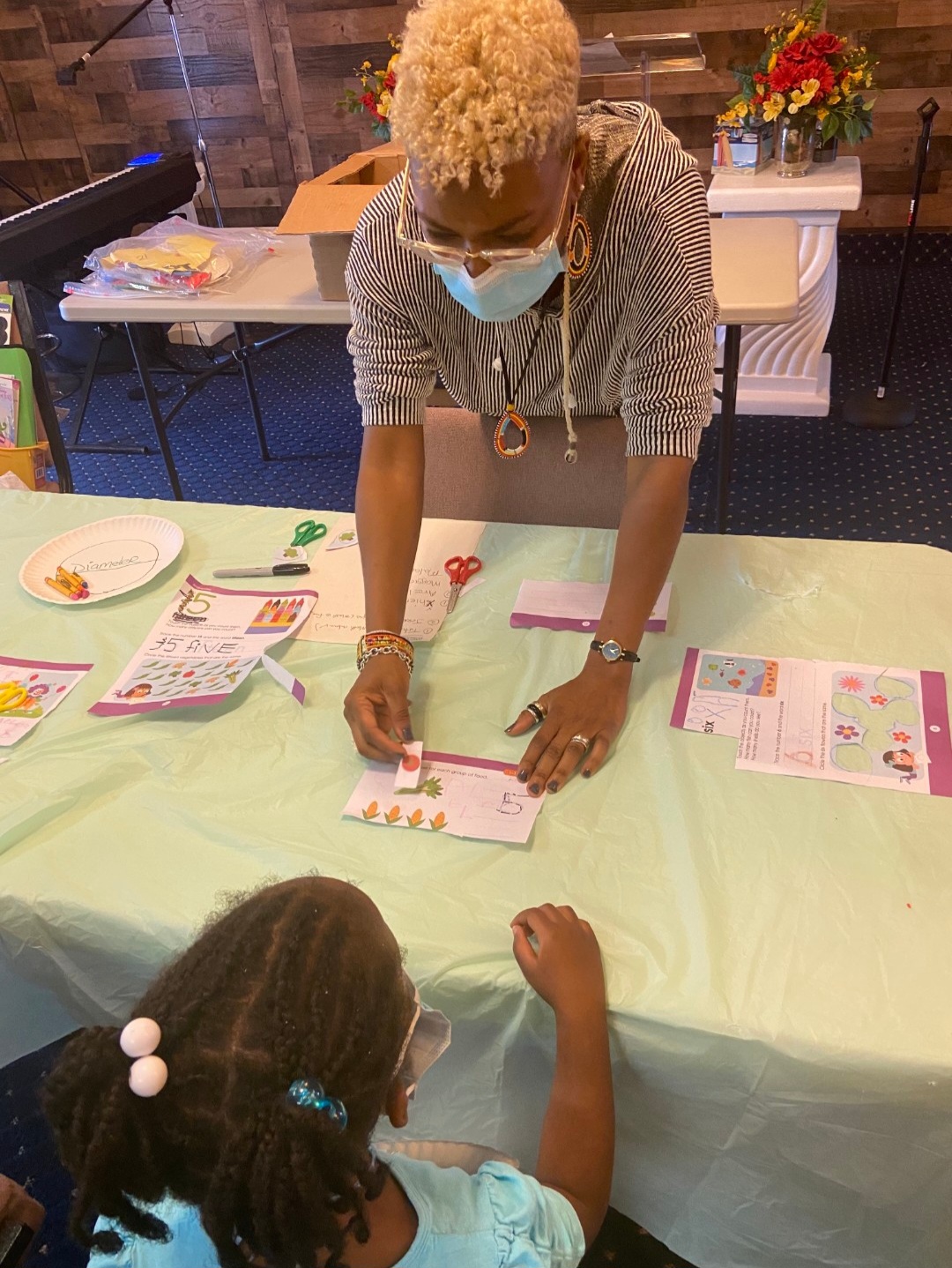Dr. GwenJ helping a child with a counting worksheet at a workshop