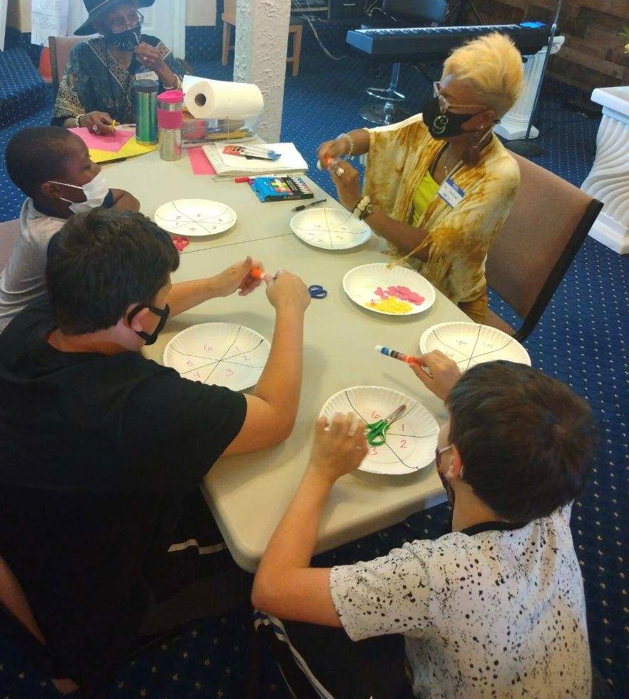 Dr. GwenJ leading a paper-plate fractions workshop with kids